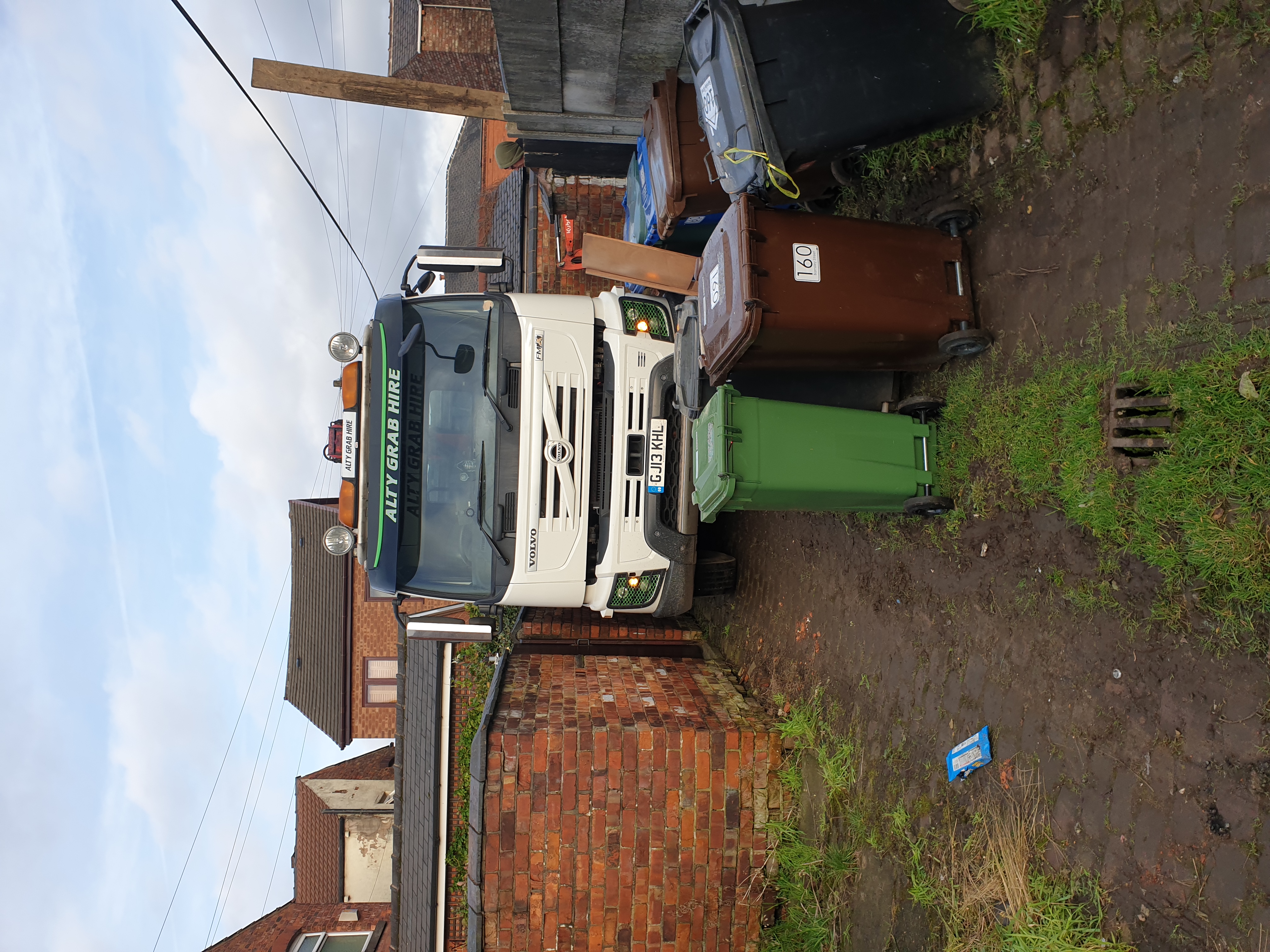 Grab hire truck delivering topsoil in a confined space.